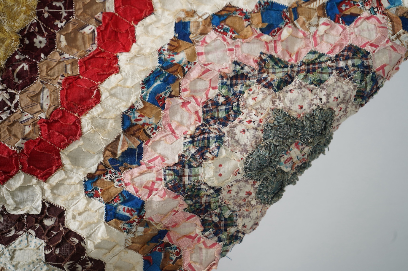 A large 19th century ‘Grandmother’s Flower Garden’ cotton patchwork bedspread, using dress fabric scraps from the day to create hexagonal concentric patterns which form a flower like shape/pattern, 282 x 254cm. Condition